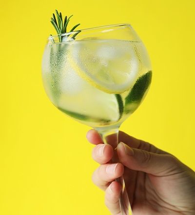 Gepflegte Hand, die ein Glas Gin Tonic hält